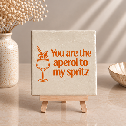 Parelmoer Aperol Spritz tegeltje met oranje tekst op houten tegelhouder
