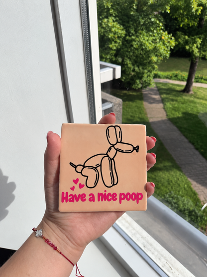 Roze tegeltje met tekst Have a Nice Poop en ballonhond